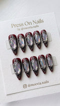 Stiletto-shaped deep red press on nails with ornate 3D silver frames and iridescent stones