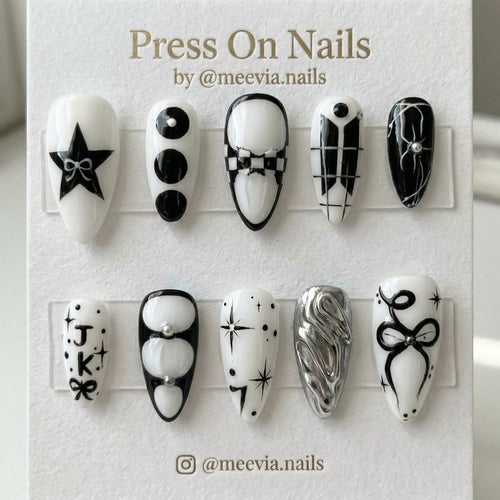 Stiletto-shaped black and white press-on nail set with stars, bows, and 3D silver chrome accents.