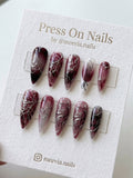 Almond-shaped press on nails featuring iridescent chrome, silver glitter, and black floral galaxy designs with 3D gold accents