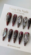 Long stiletto-shaped burgundy and black press-on nail set with 3D silver molten art and iridescent shell inlays