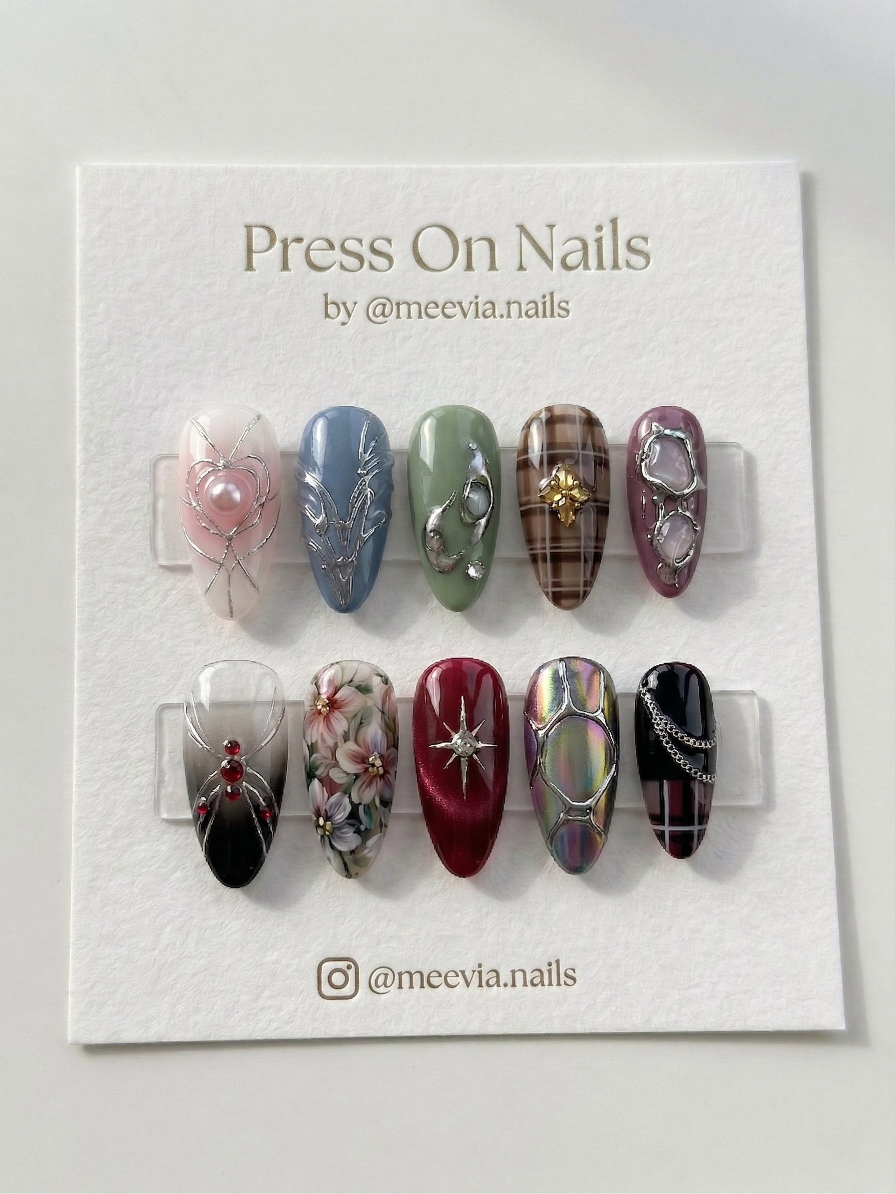 Almond-shaped press on nail set with eclectic 3D designs including hearts, plaid, and florals