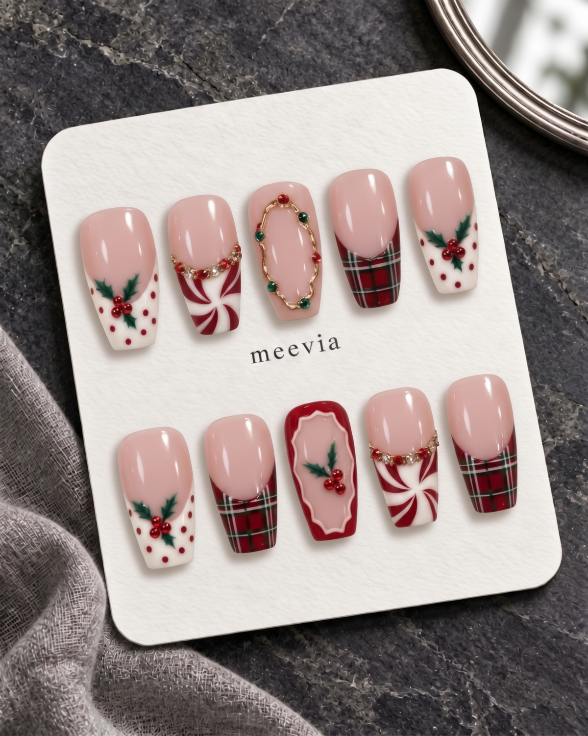Pink Christmas press-on nails with plaid tips, holly berries, peppermint swirls, and glossy finish