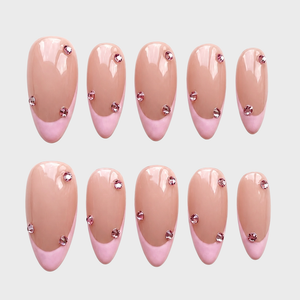 Pink French tip press-on nails decorated with small pink rhinestones.