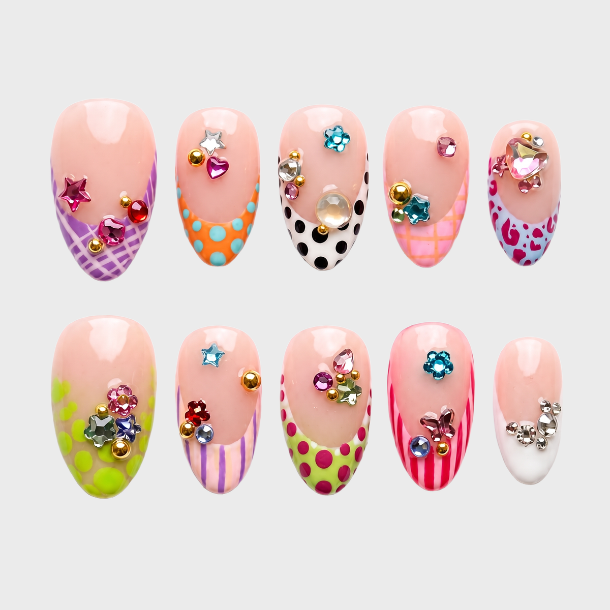 A set of press-on nails featuring French tips with colorful polka dot, stripe, and leopard patterns decorated with 3D rhinestones and charms.