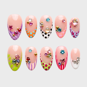 A set of press-on nails featuring French tips with colorful polka dot, stripe, and leopard patterns decorated with 3D rhinestones and charms.