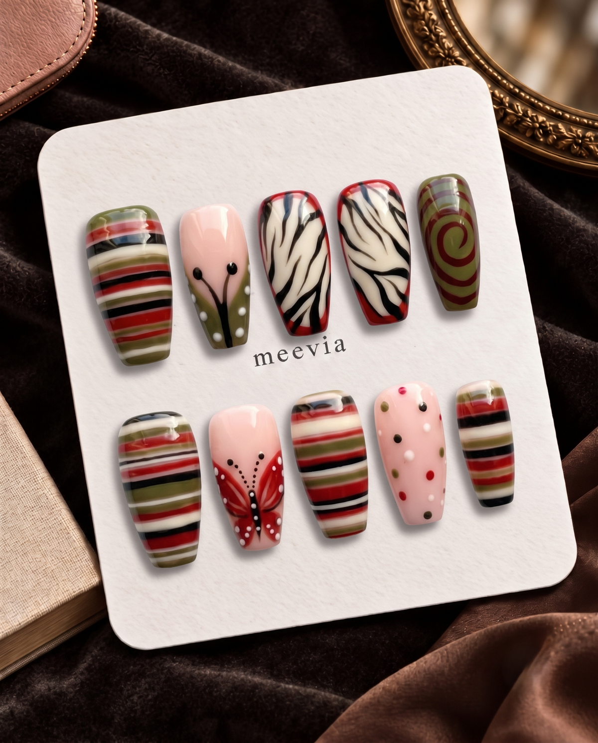 Glossy red and olive striped press-on nails with butterfly and zebra-inspired designs