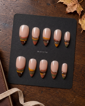 Nude press-on nails with retro multicolor striped French tips, silver stars, and rhinestone accents
