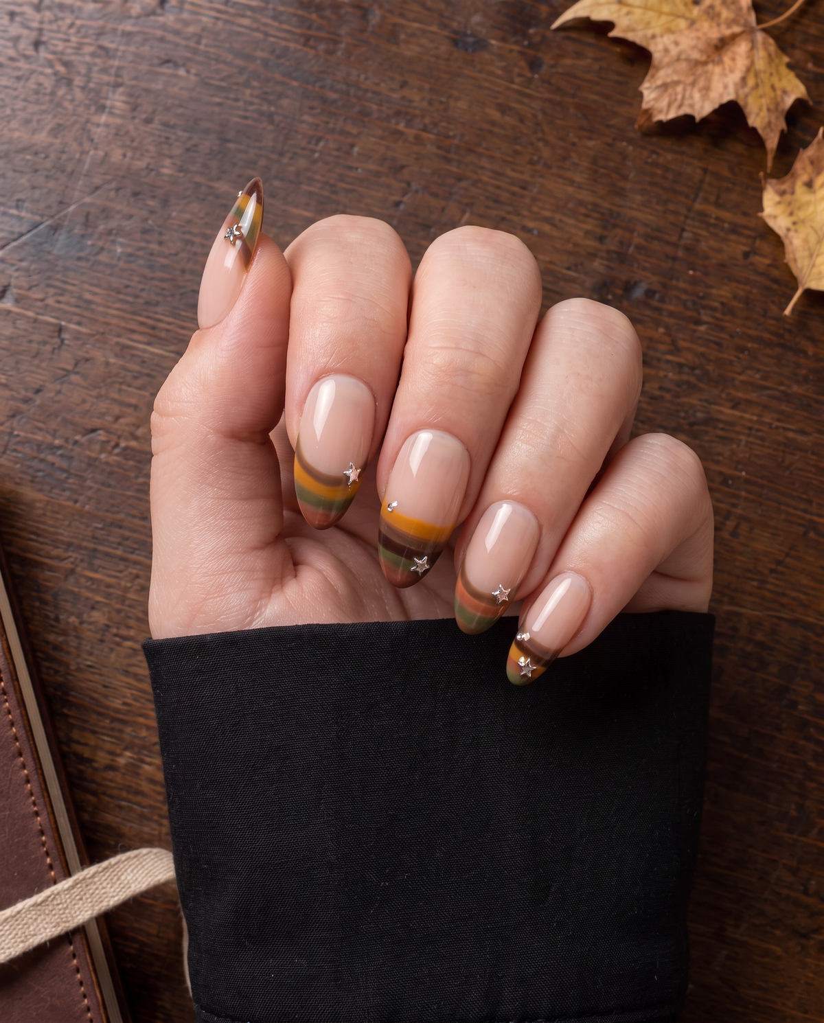 Nude press-on nails with retro multicolor striped French tips, silver stars, and rhinestone accents