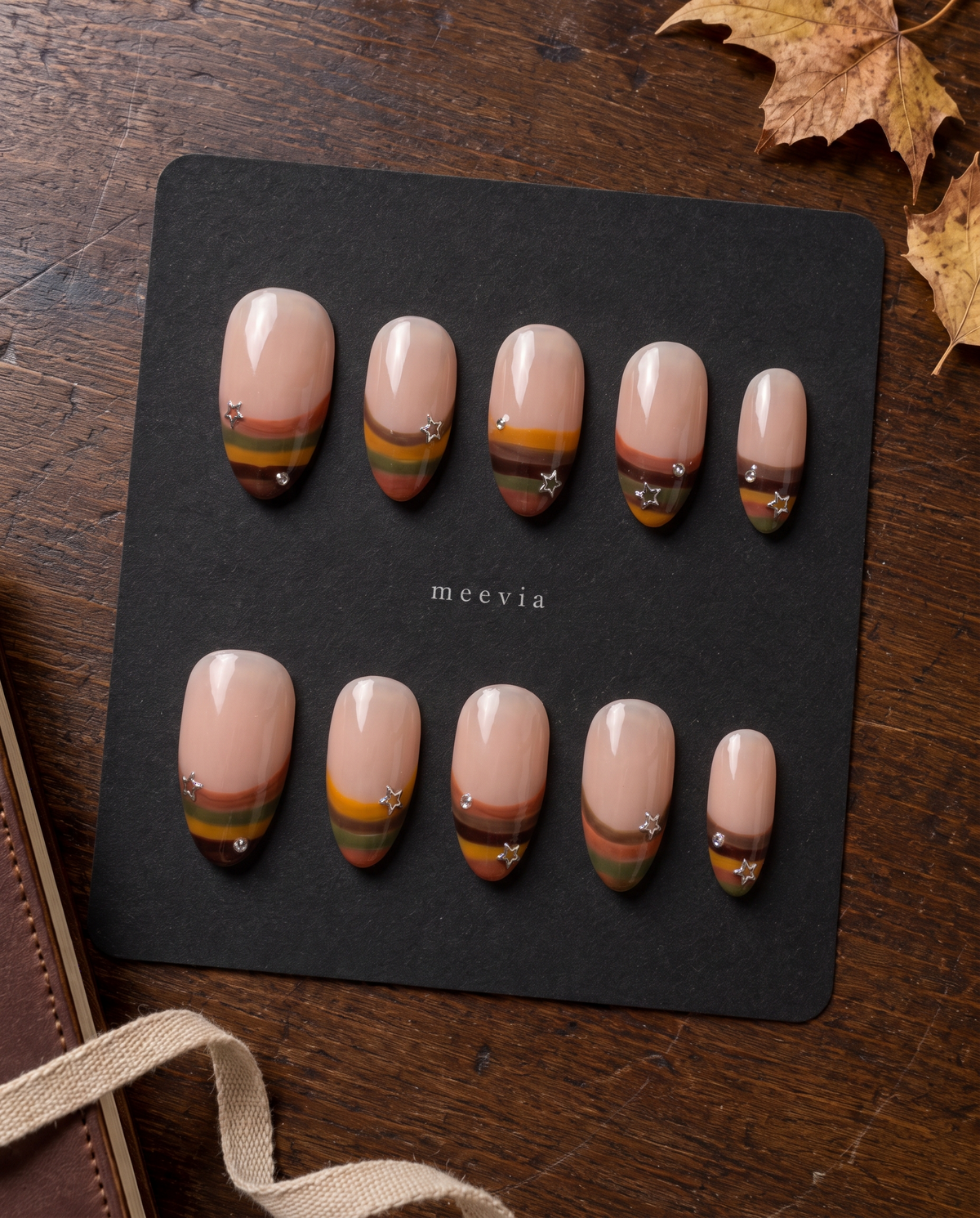 Nude press-on nails with retro multicolor striped French tips, silver stars, and rhinestone accents
