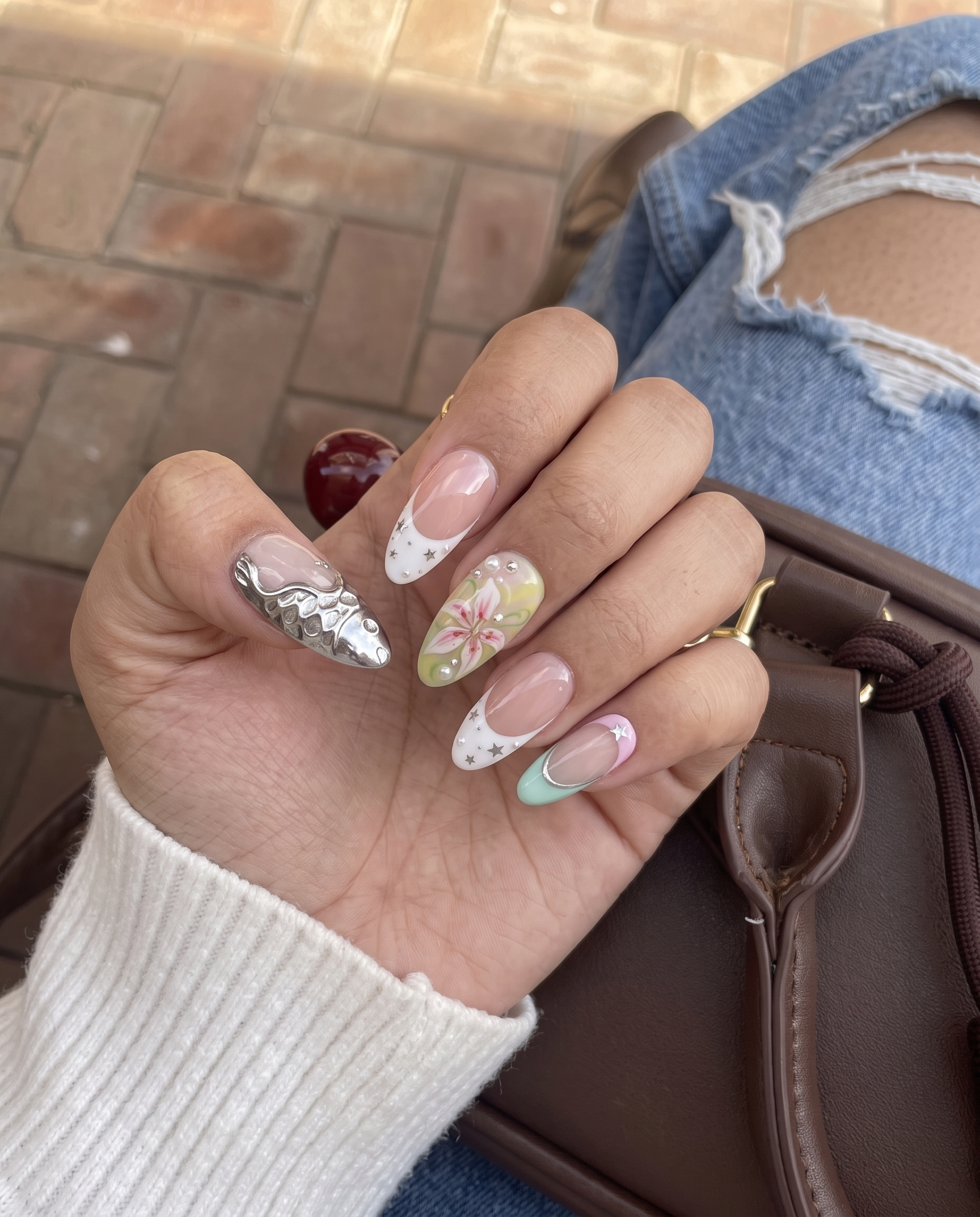 Pastel mermaid press-on nails featuring silver metallic fish scales, colorful star gems, and a pink lily flower design.