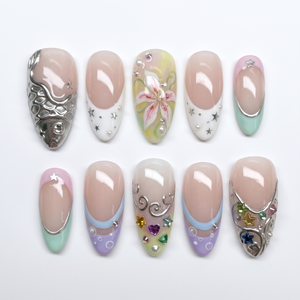 Pastel mermaid press-on nails featuring silver metallic fish scales, colorful star gems, and a pink lily flower design.