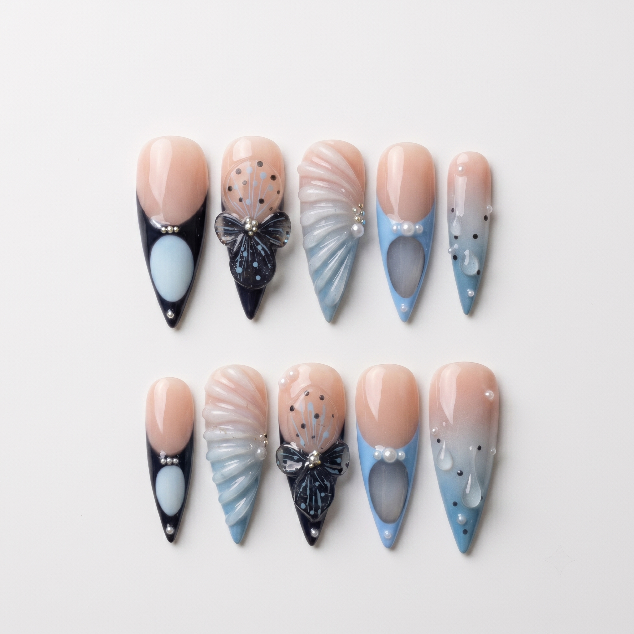 Set of stiletto press-on nails featuring blue and black French tips, butterfly art, pearl accents, and 3D shell textures.