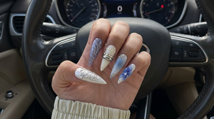 A set of press-on nails featuring blue floral designs, 3D silver chrome butterfly wings, and metallic ring accents.