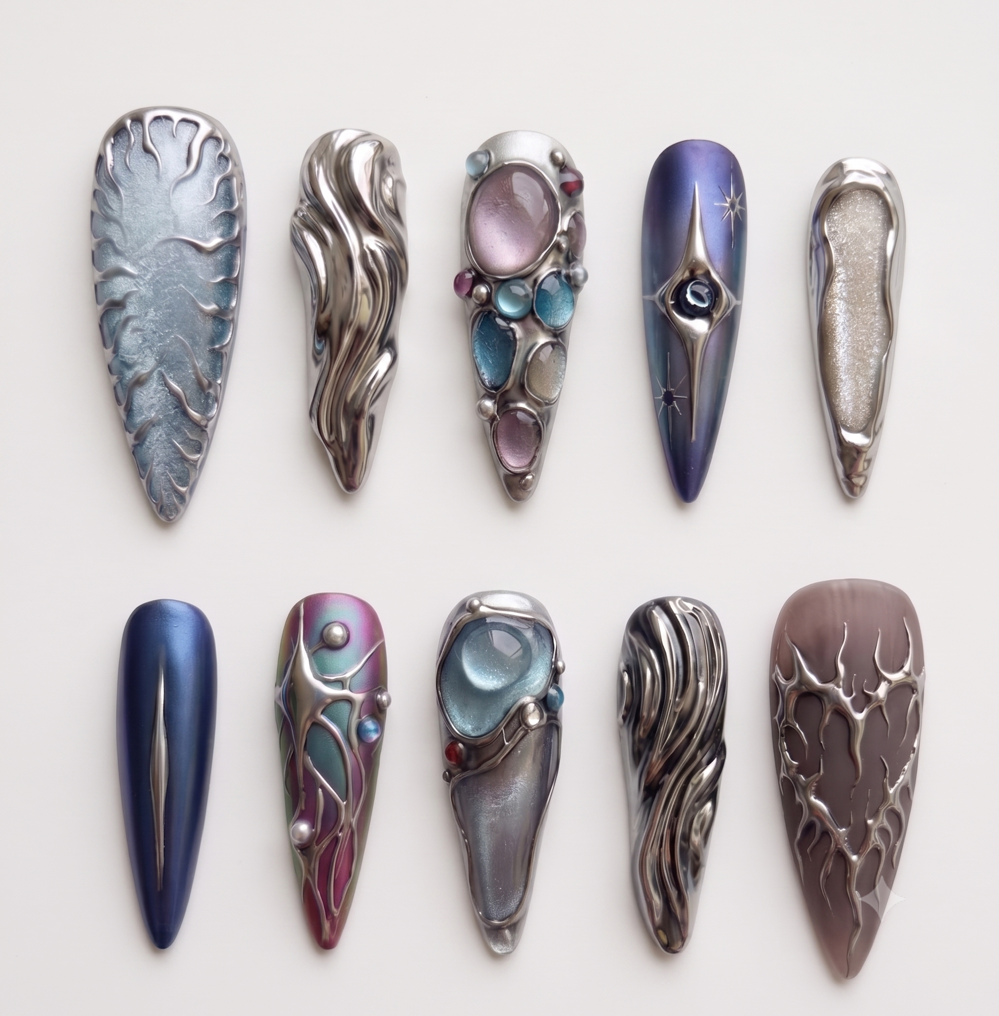 A set of ten stiletto-shaped press-on nails with silver metallic liquid textures, celestial star designs, and embedded colorful gemstones.