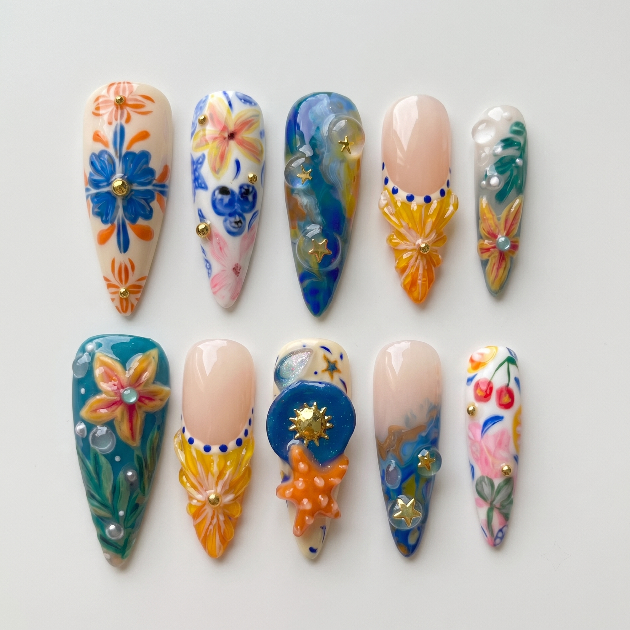 A set of ten stiletto-shaped press-on nails featuring a Mediterranean summer theme with 3D starfish, sun charms, yellow flowers, blue tile patterns, and ocean wave designs.