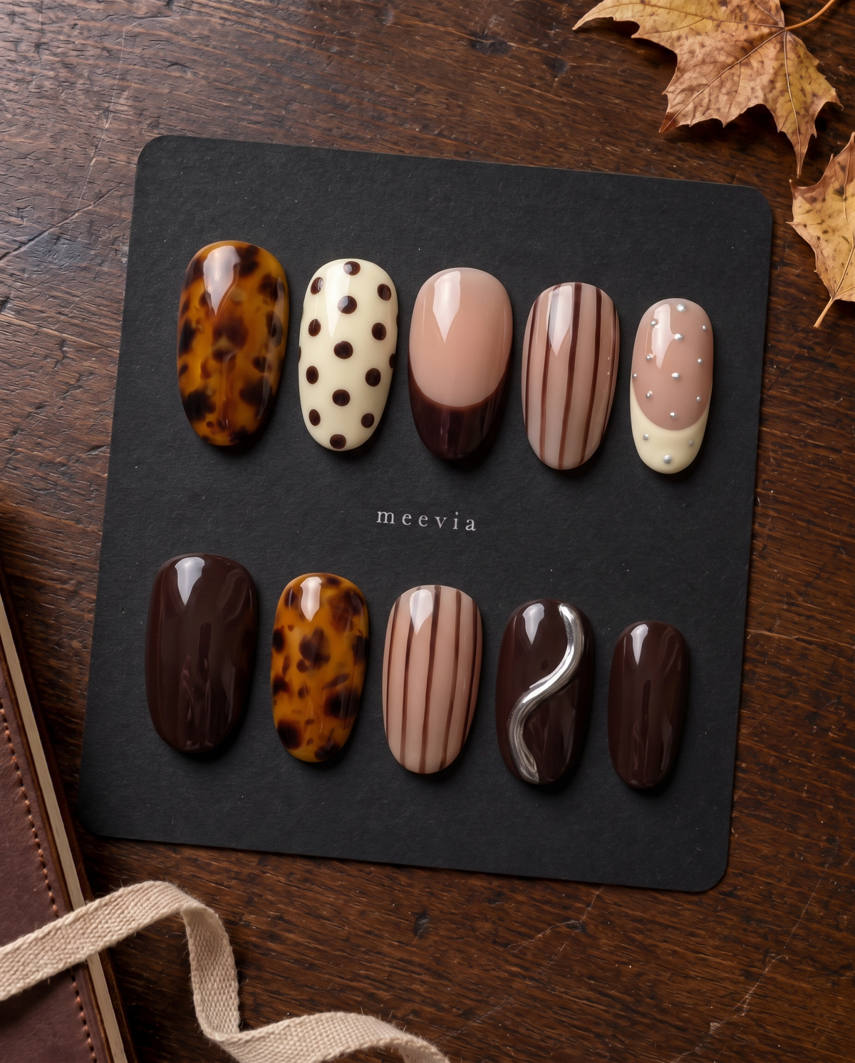 Brown tortoiseshell and striped press-on nails with glossy nude, ivory, and chocolate designs