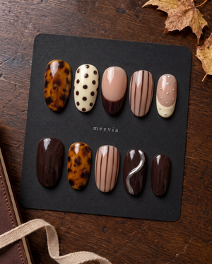 Brown tortoiseshell and striped press-on nails with glossy nude, ivory, and chocolate designs
