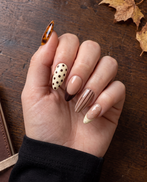 Brown tortoiseshell and striped press-on nails with glossy nude, ivory, and chocolate designs