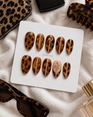 Glossy tortoiseshell press-on nails with gold edging, moon and star details, and a snake accent