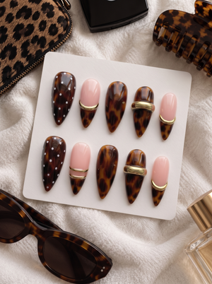 Brown tortoiseshell and pink press-on nails with gold bands and white dot details