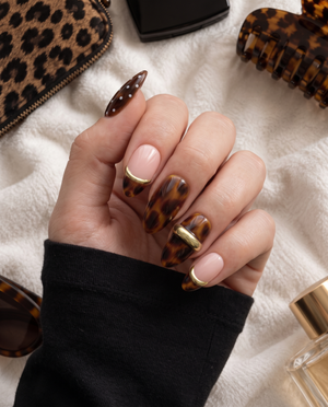 Brown tortoiseshell and pink press-on nails with gold bands and white dot details