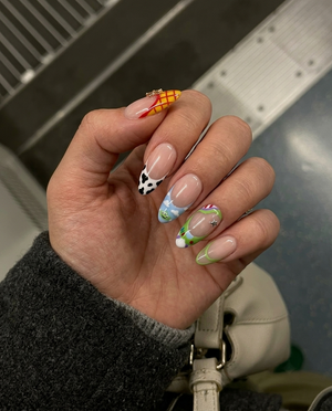 Toy Story inspired press-on nails with character themed French tips and star charms.