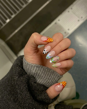 Toy Story inspired press-on nails with character themed French tips and star charms.